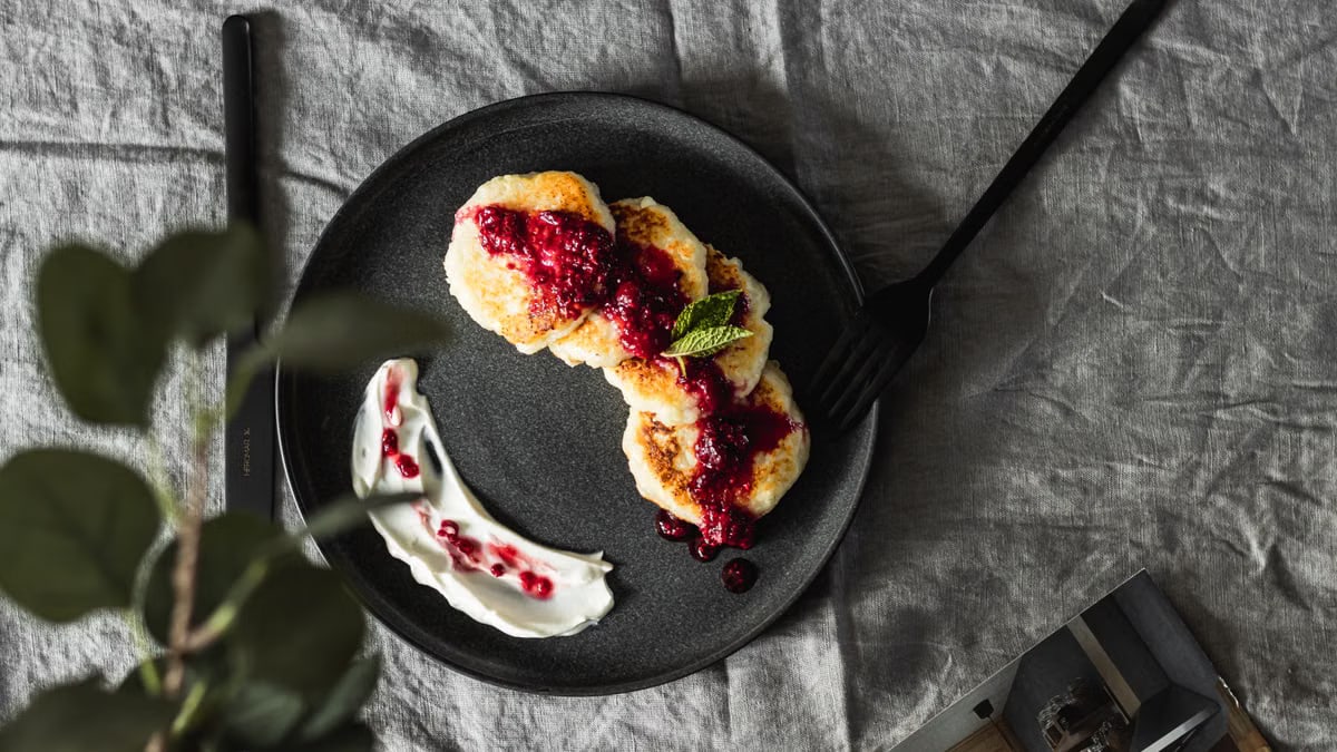 Tasty pancakes topped with fresh berry sauce on a ceramic plate, perfect for a gourmet breakfast.